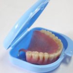 What are the functions of a container for dentures?